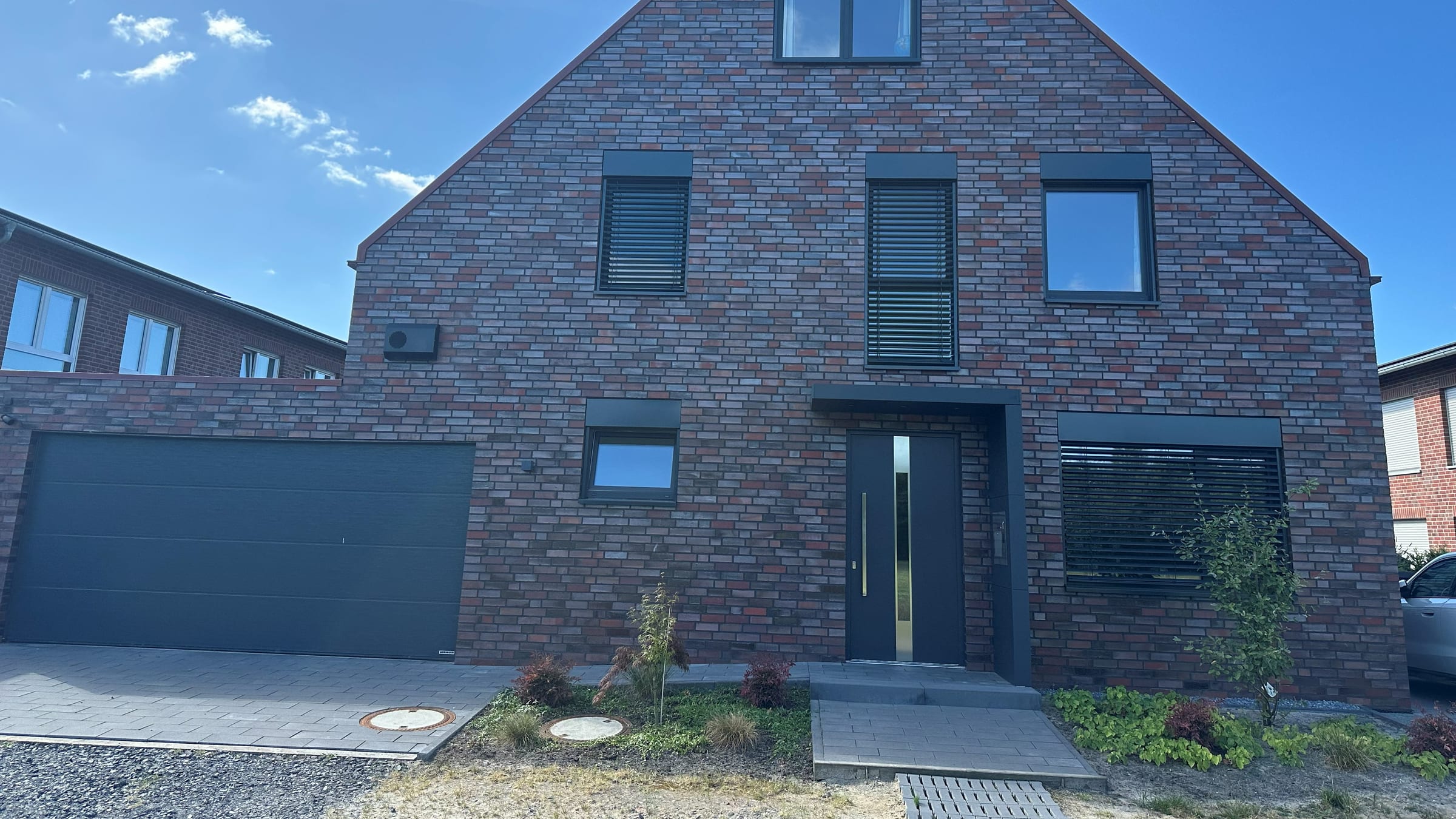 Fassade unseres Hauses mit automatisch heruntergefahrenen Raffstores an zwei Fenstern
