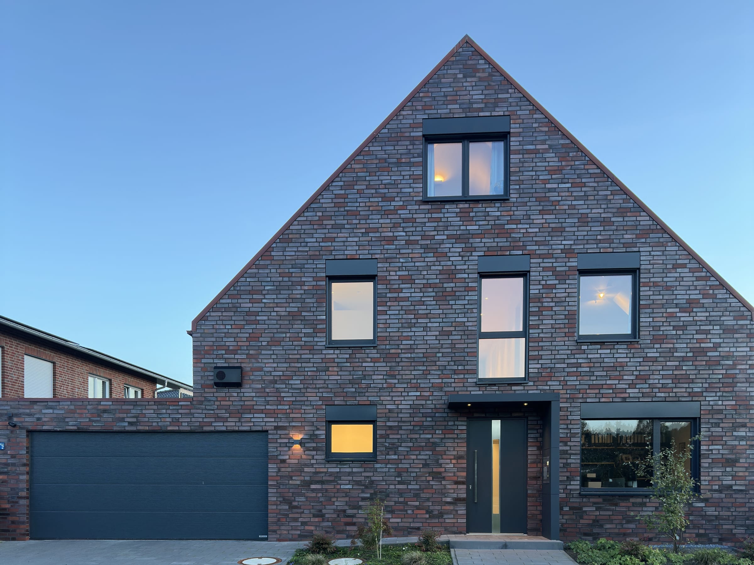 Unser Wohnhaus in Hörstel zur blauen Stunde, Fenster von innen beleuchtet, mit Eingang und Garage