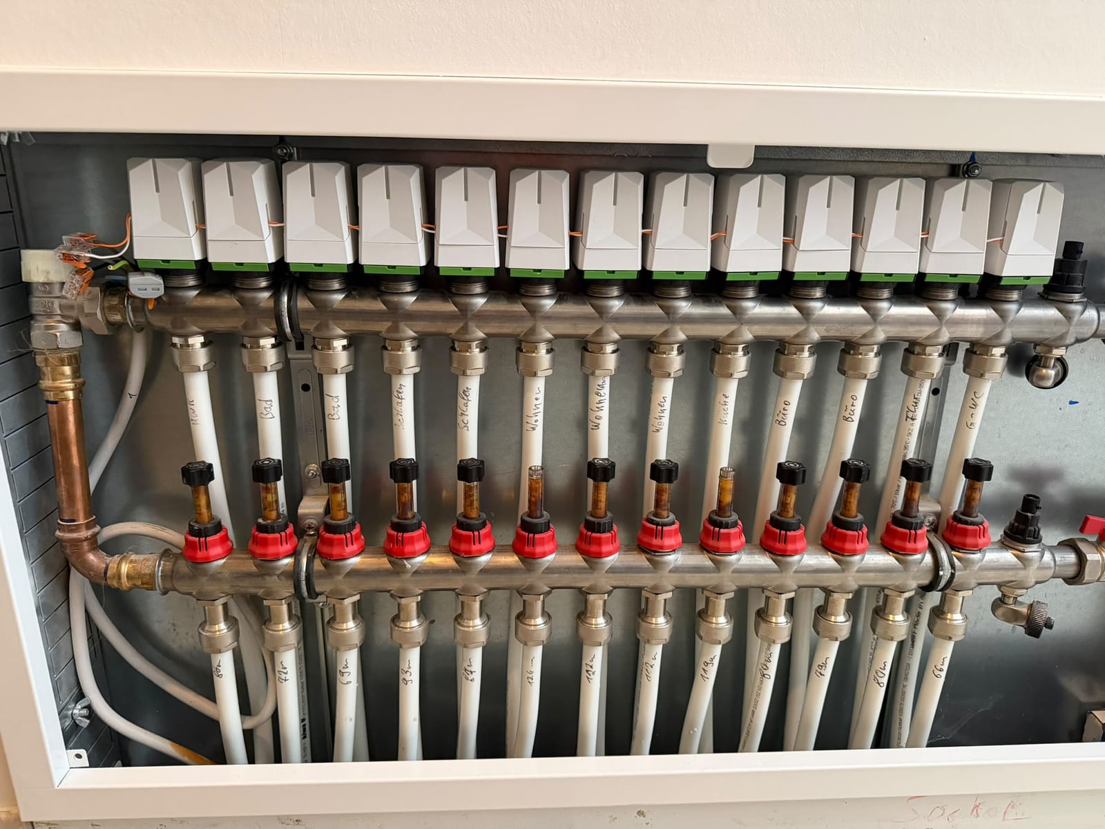 Heizkreisverteiler mit 13 Loxone-Stellantrieben und beschrifteten Heizkreisen
