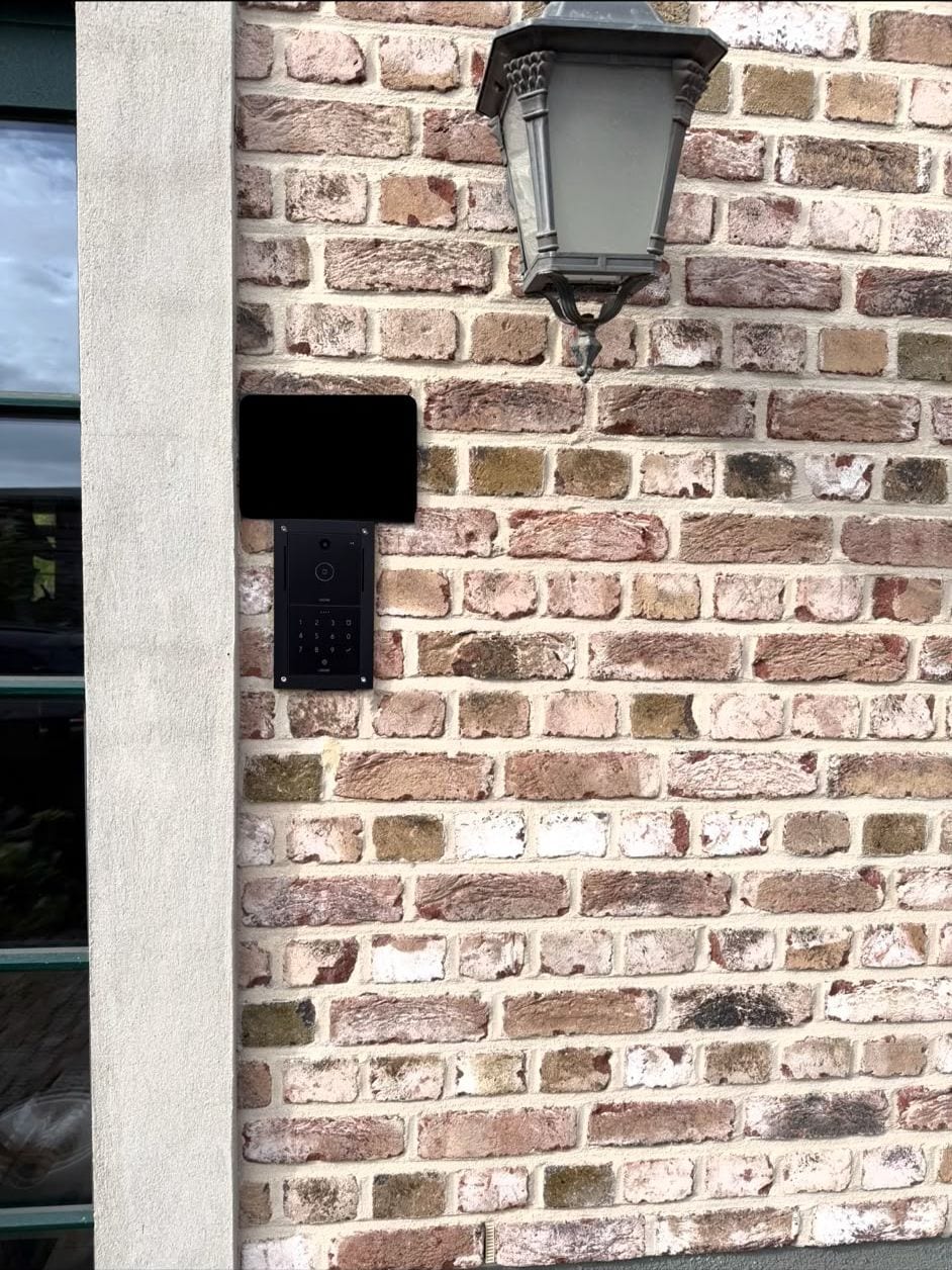 Schwarze Loxone Intercom mit Tastenfeld an einer Klinkerwand unter einer Außenleuchte
