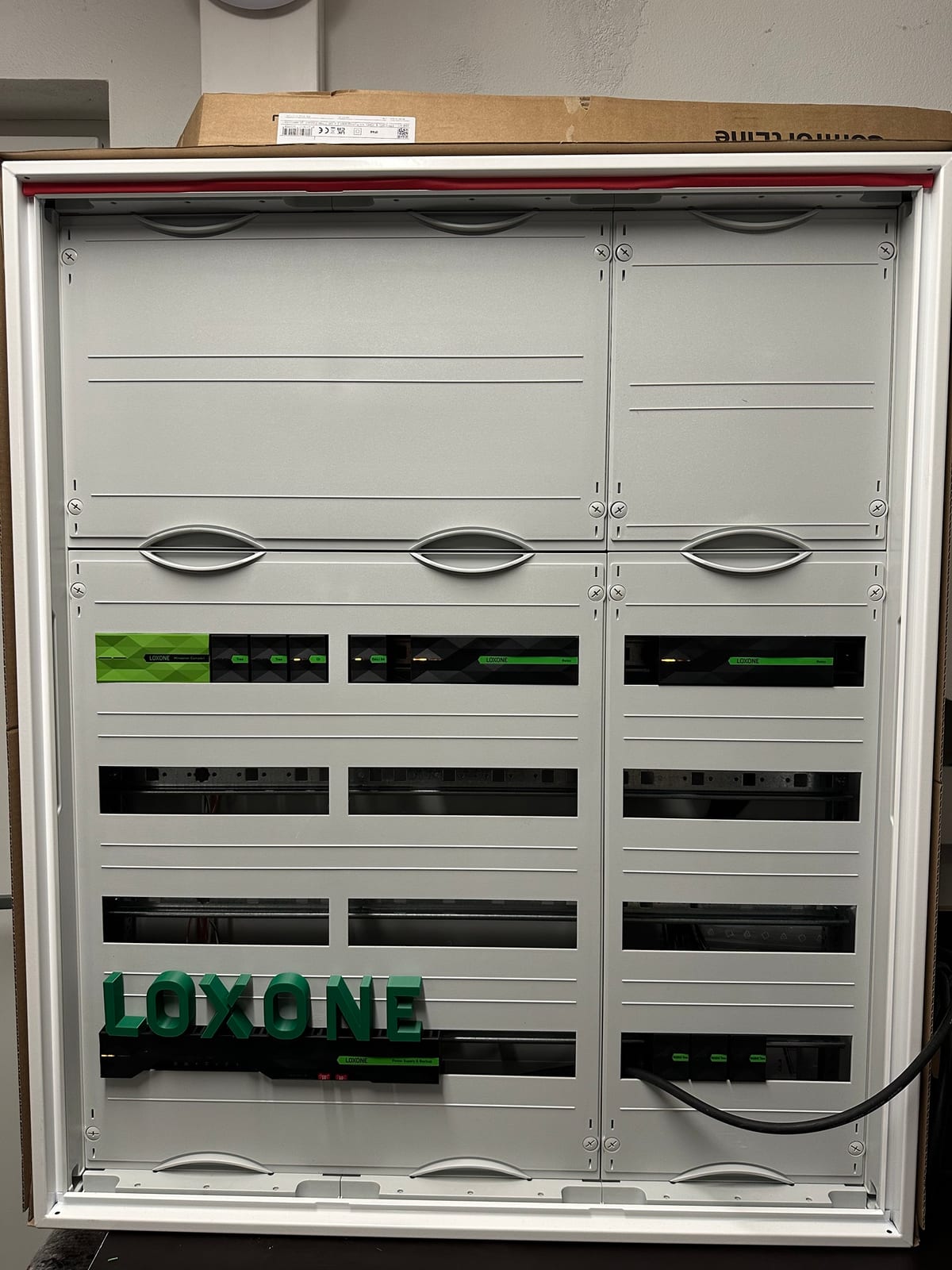 Derselbe Schaltschrank mit Abdeckungen, die Loxone-Module schauen durch die Ausschnitte