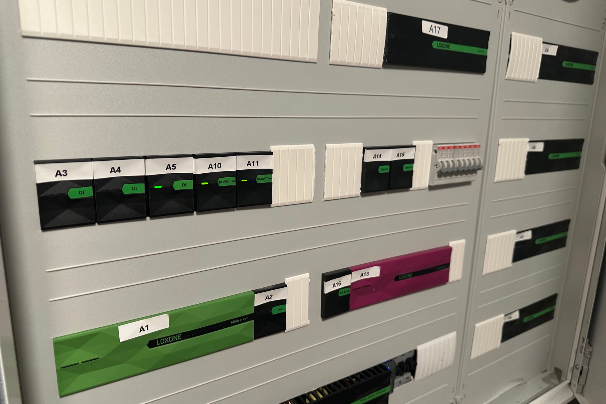 Geöffneter Loxone-Schaltschrank mit grünem Miniserver und beschrifteten Modulen