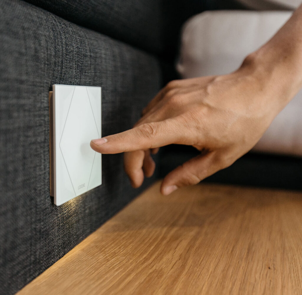Mensch klickt auf Taster um das Smart Home zu steuern.